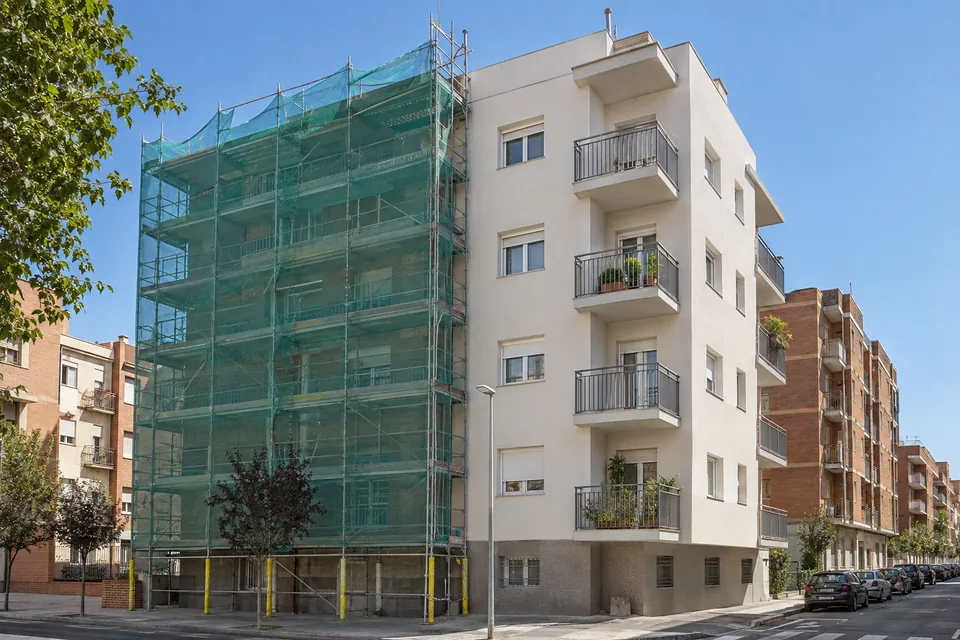 Bloc de pisos dels anys 70 amb bastida durant una rehabilitació energètica de la façana